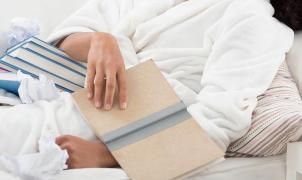 Una persona tumbada en la cama mirando libros