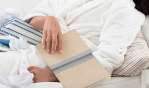 Una persona tumbada en la cama mirando libros