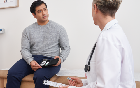 Paciente en consulta médica con equipo de monitoreo de diabetes.