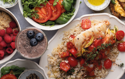 Un plato de arroz con tomate y pescado blanco, decorado con hierbas frescas.